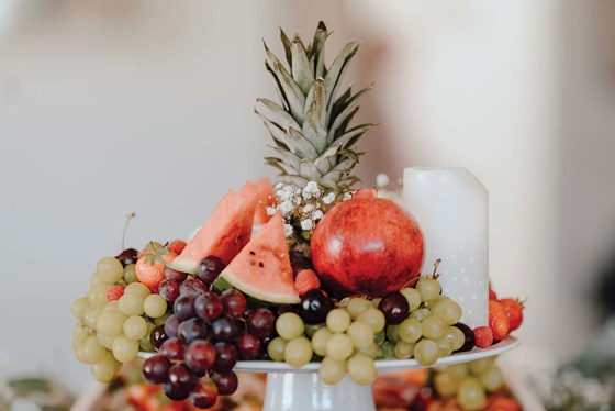 Elevated area of grazing table at wedding with fruits such as pineapple, grapes, pomegranate and watermelon